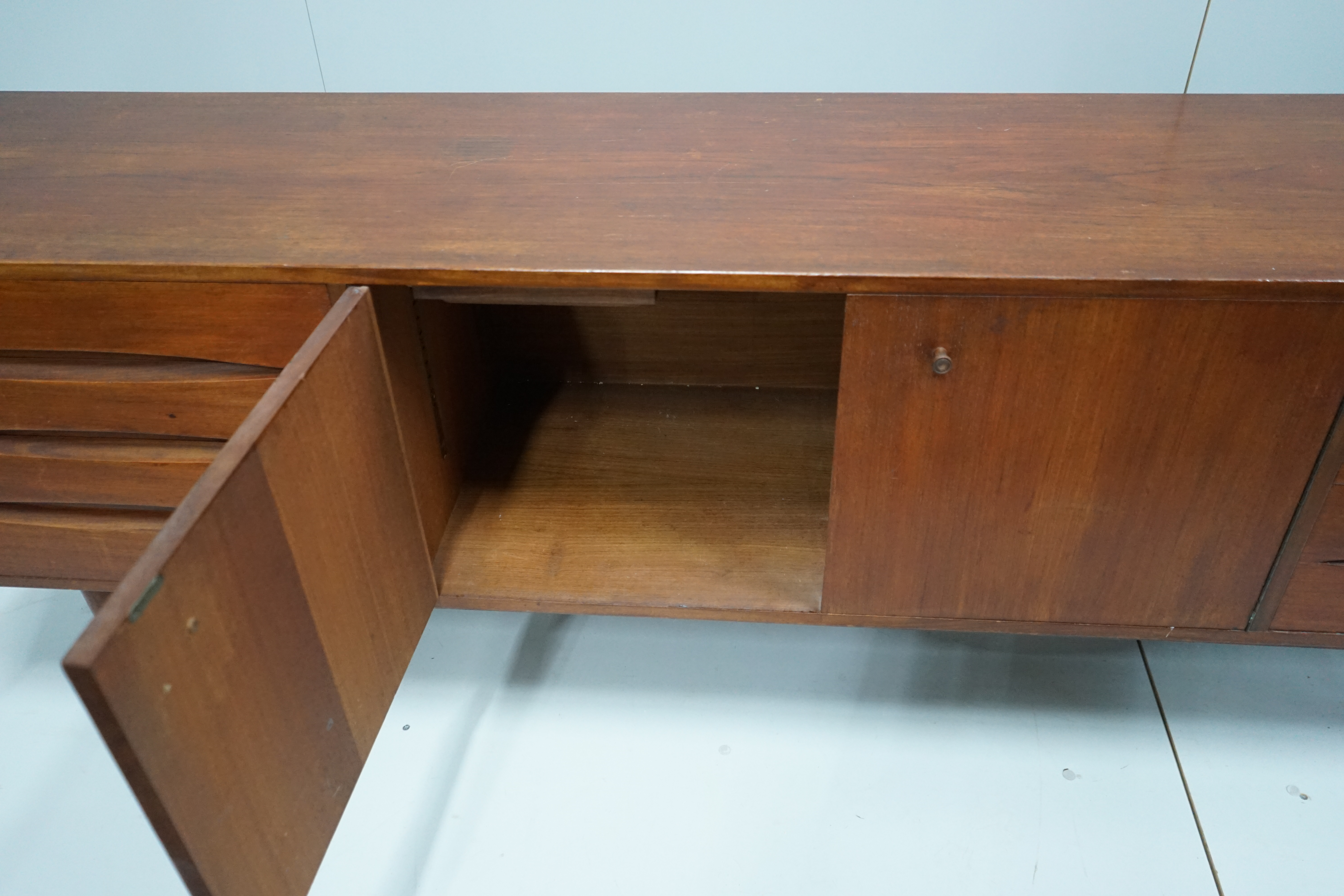 In the manner of Arne Vodder, a mid century teak sideboard width 221cm, depth 45cm, height 73cm.